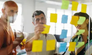 Zespół planuje strategię, analizując zadania na kolorowych karteczkach. To przykład, jak outsourcing może usprawnić pracę.