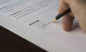 Podpis na umowie zlecenia. Dokument zawiera klauzulę o podstawie prawnej rozwiązania umowy.