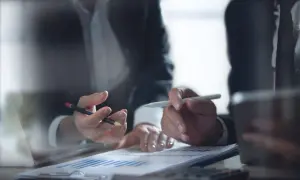 Dwie osoby analizują wykresy, dyskutując o strategii sprzedaży długów.