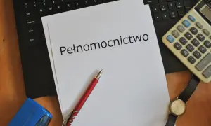 Dokument "Pełnomocnictwo" leży na klawiaturze obok długopisu, kalkulatora i stempla.